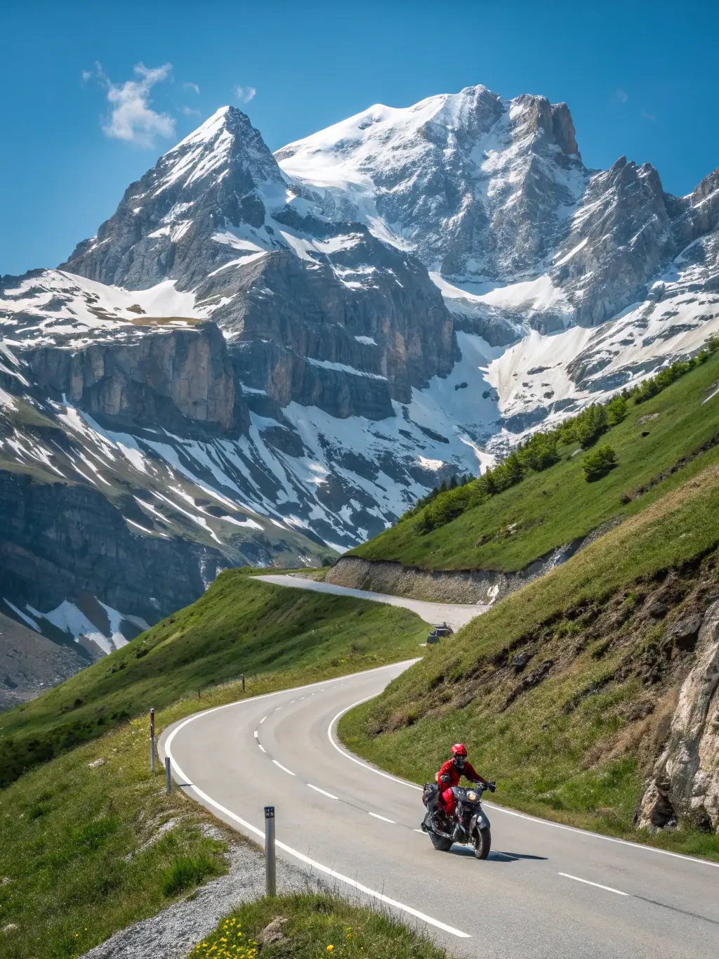 A motorcyclist standing next to their bike on a mountain road during a multi-day trip, with scenic views in the background.